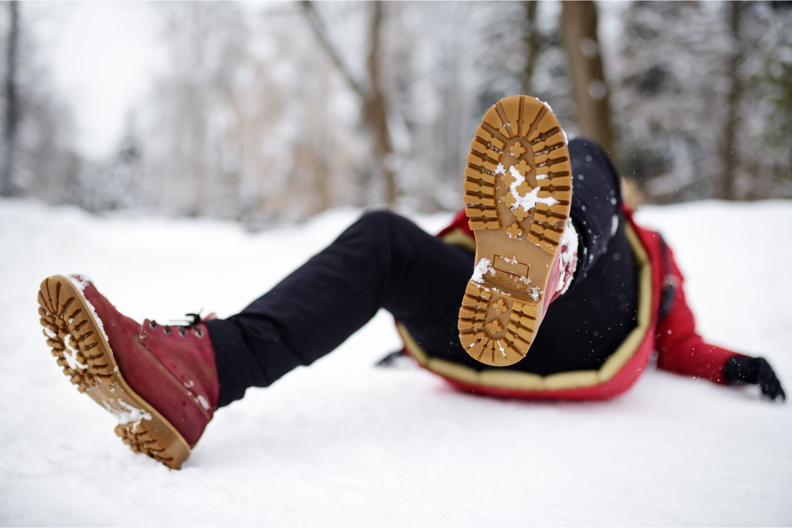 Person laying in snow with boots towards camera after falling