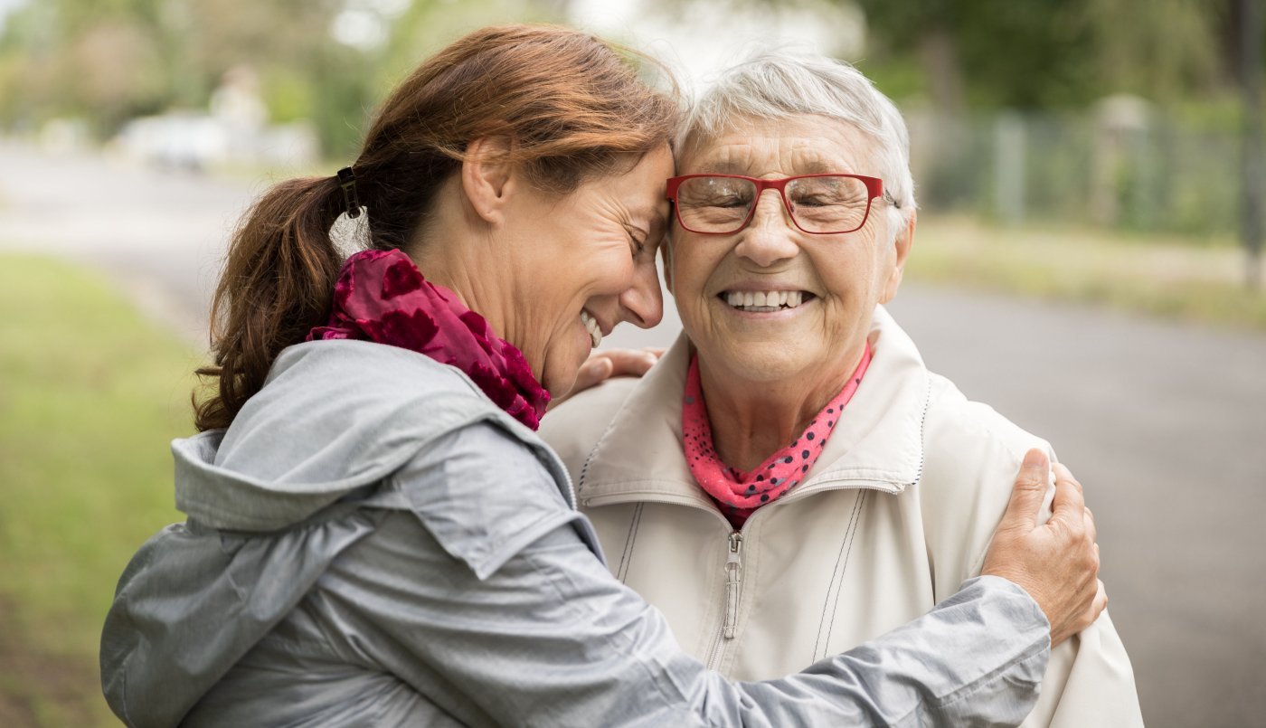 female caregiver embracing elderly woman